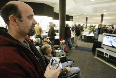 
Larry Santo of Omaha, left, holds a can of beer as he watches a movie on a wide screen television at Borsheim's. Santo was among the hundreds of men who came out for men's night at Borsheim's, which uses free pizza and beer to counteract the otherwise intimidating notion of buying jewelry.
 (The Spokesman-Review)