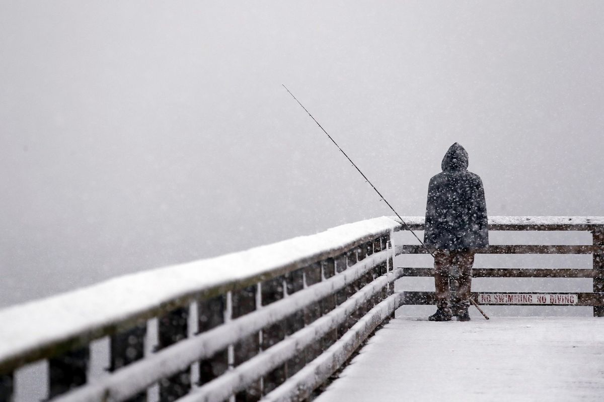 Hershel Odle looks out toward the cityscape lost in a whiteout as he fishes from a pier during a snowstorm Friday, Feb. 8, 2019, in Seattle. (Elaine Thompson / AP)
