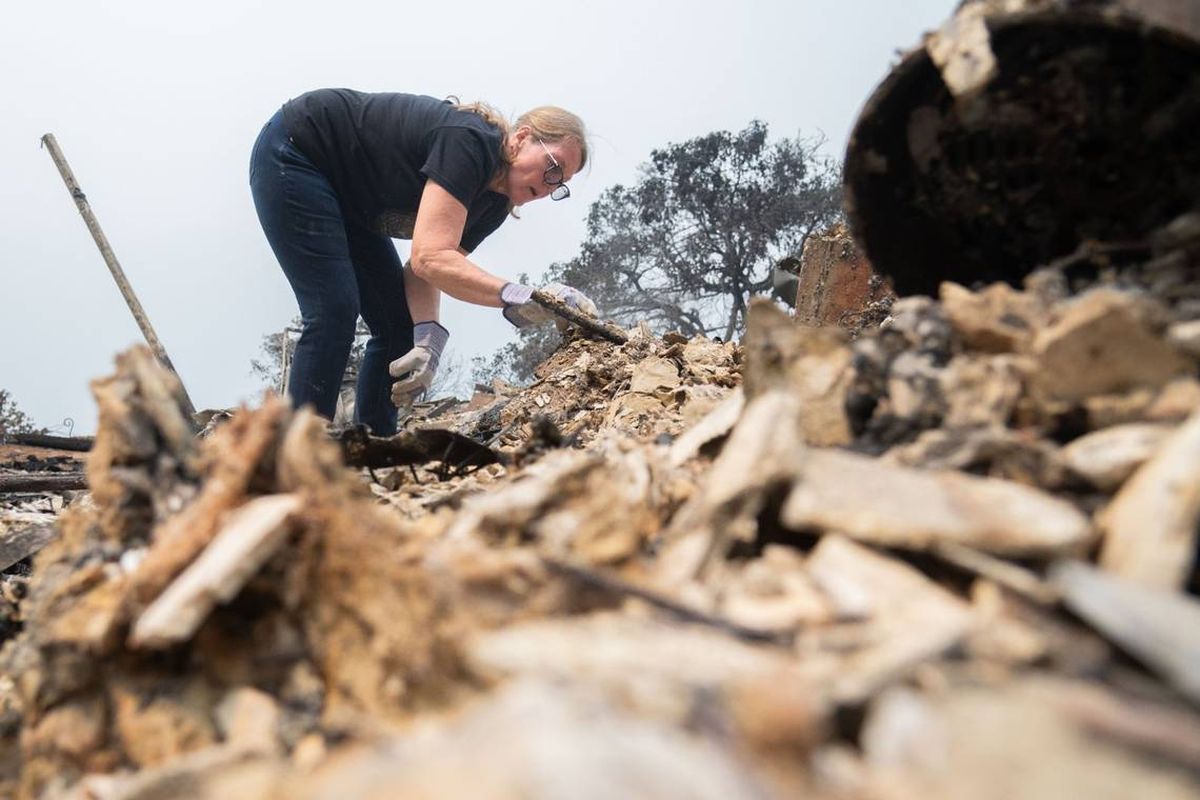 Linda Fischer picks through debris at her home in Forest Ranch on Wednesday. Although her neighbors’ homes were largely untouched by the Park Fire, hers was completely destroyed.  (Bailey Stover/The Sacramento Bee/TNS)