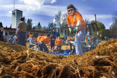 
Rosene Hurd attacks a huge pile of mulch as she joins with over 125 other volunteers to build a new playground for the Martin Luther King Jr. Family Outreach Center in Spokane on Thursday. 
 (Christopher Anderson/ / The Spokesman-Review)
