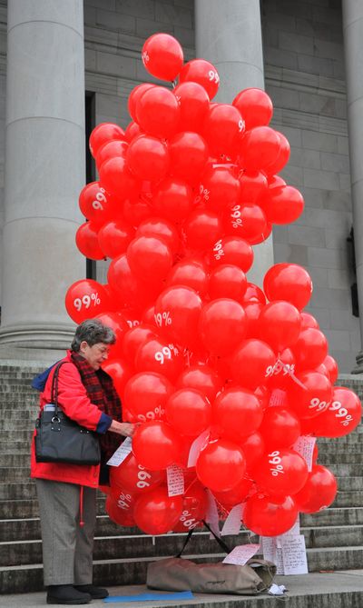 Chris Clark, of Deer Park, ties a list of concerns over proposed cuts in the state budget to the string of helium balloons Tuesday on the state Capitol steps. Protesters had planned to bring the balloons inside and let them loose, so they’d rise to the top of the dome, but state officials said the balloons wouldn’t be allowed inside. They tied them into a tree shape and tied them to a weight outside. (Jim Camden)