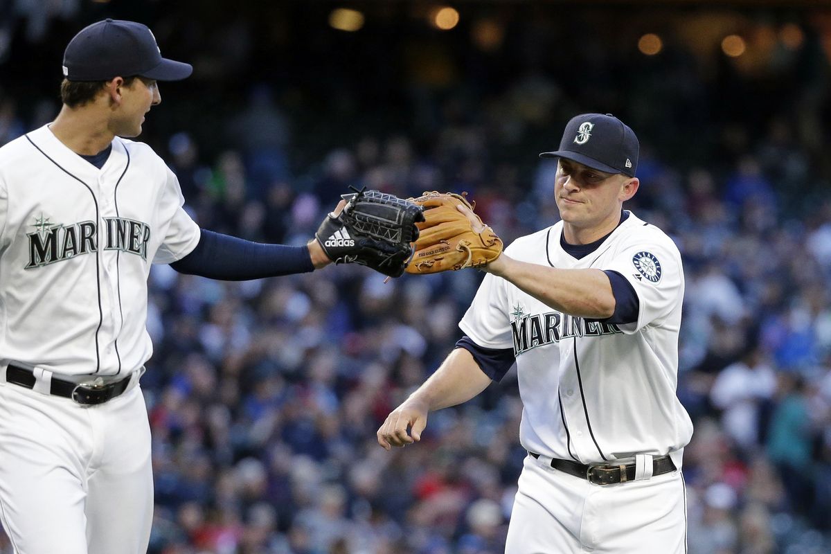 Mariners starting pitcher Chase De Jong, left, taps his glove to the glove of third baseman Kyle Seager after Seager snagged a line drive by Texas Rangers’ Delino DeShields in the fifth inning. (Elaine Thompson / Associated Press)