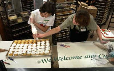 
Shadle Park High School DECA student Amalie Marte, left, gets a helping hand from Nataliya Kuropatko, a cake decorator at the Shadle Safeway, on Thursday morning. The DECA students staffed various departments including the bakery, fueling station and the deli. 
 (Dan Pelle / The Spokesman-Review)