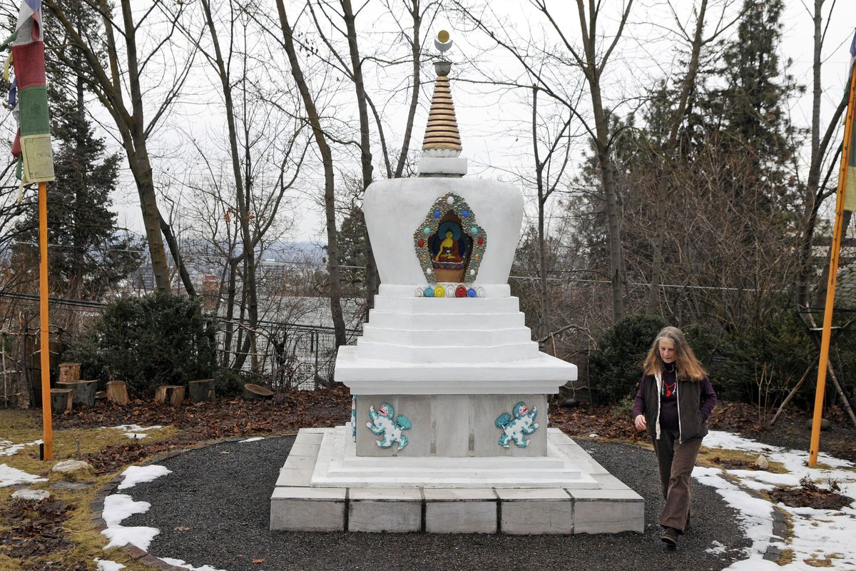 Inge Sandvoss, a Buddhist lama, walks respectfully clockwise around the stupa in her backyard on Friday on Spokane’s South Hill. The copper canopy that covers part of the top section of the Buddhist stupa has been stolen. (PHOTOS BY DAN PELLE)