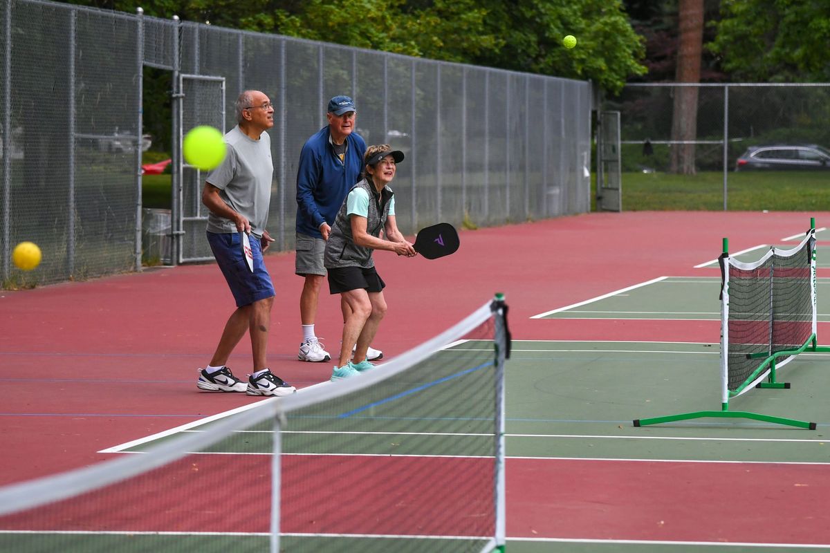 The balls were flying for pickleballers, from left, Aziz Tajuddin, Ed Haskell and Jeanie Haskell gather at the Comstock Park tennis courts for a warmup before playing, Friday, July 15, 2022, in Spokane.  (Dan Pelle/The Spokesman-Review)