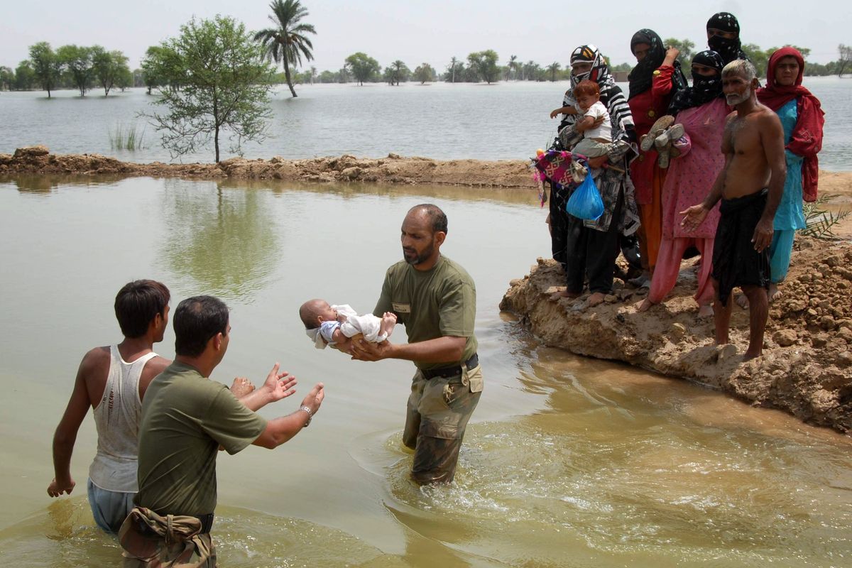 Pakistan army soldiers  help people flee  their flooded village in Taunsa near Multan, Pakistan, on Sunday.  (Associated Press)