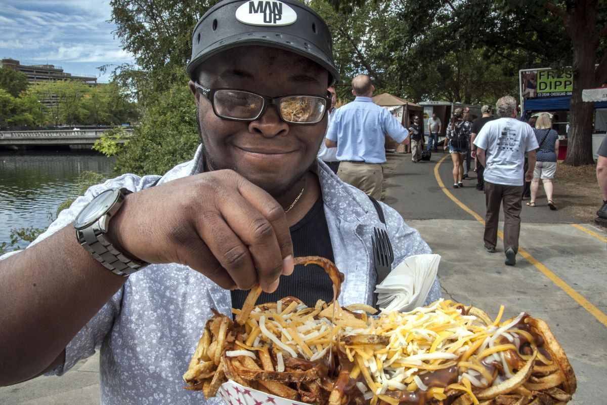 Avery Monroe delights in a giant serving of Canadian fries at last year’s Pig Out in the Park. (Dan Pelle / The Spokesman-Review)