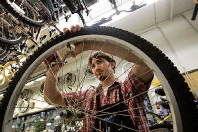 
 Matt Tkachuck, a bicycle technician, checks out a wheel at an REI store  in Seattle. 
 (The Spokesman-Review)