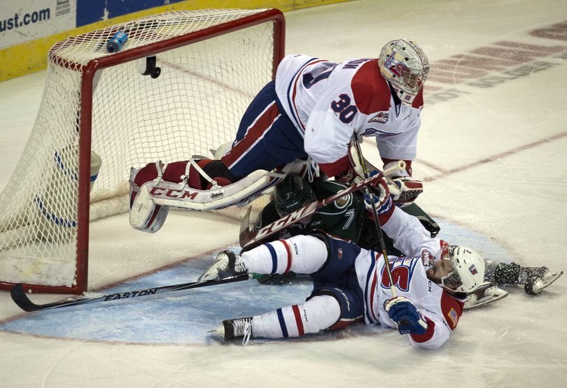 Spokane Chiefs goalie Garret Hughson (30), Everett Silvertips defenseman Tristen Pfeifer (7) and Spokane Chiefs defenseman Nick Charif (3) slide into the net during the first period of a WHL hockey game at the Spokane Arena, Wed., April 1, 2015, in Spokane, Wash. Charif went to the penalty box with a hooking call. (Colin Mulvany / The Spokesman-Review)