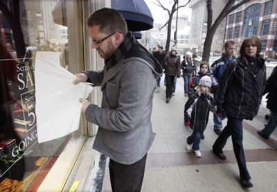 John King, visual coordinator for the Brooks Brothers store on Chicago’s Magnificent Mile, reveals a new sale decal on the window Friday that raises the previous sale discount from 40 percent off to 50 percent off.  (Associated Press / The Spokesman-Review)