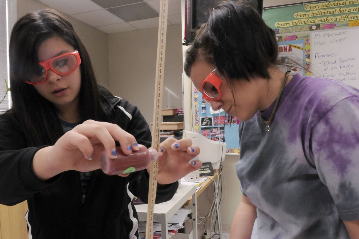 Eighth-graders Katelyn Sage and Maria Stazel work as a team to determine how height and angle could affect the relationship between the diameter and shape of blood spatters during a forensic class  at Centennial Middle School March 15. (J. BART RAYNIAK)