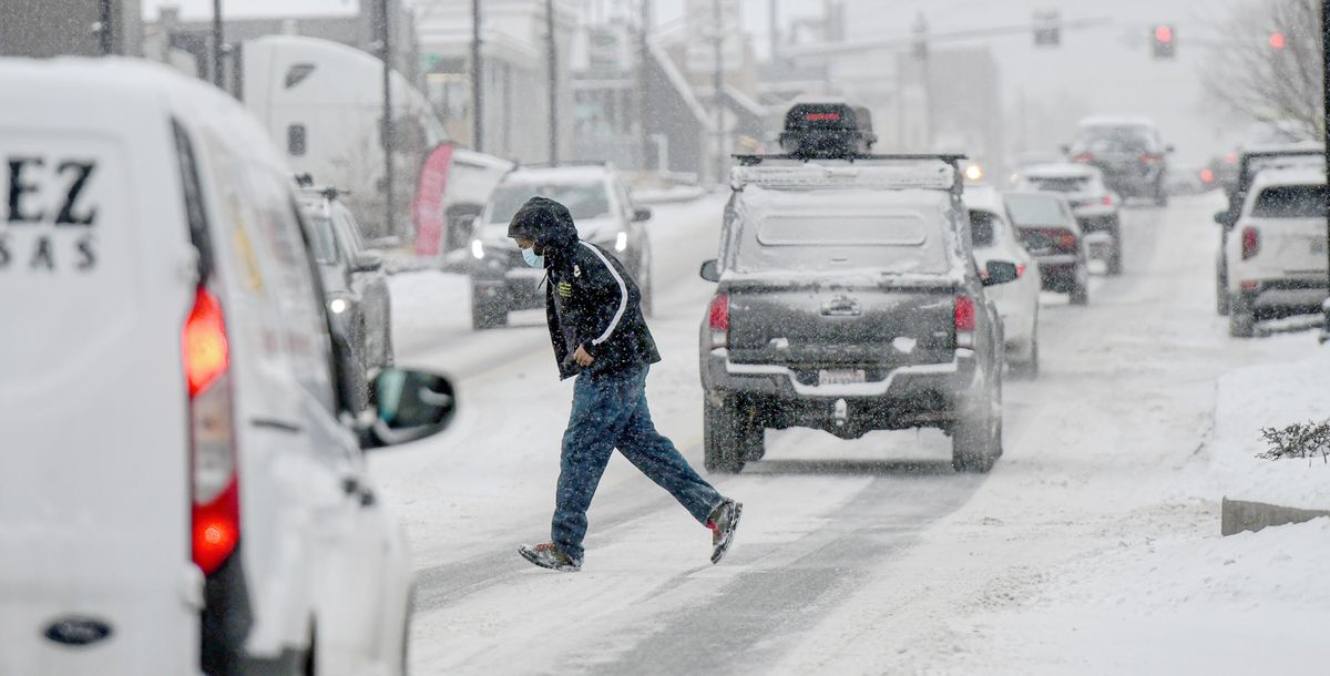 A person crosses North Monroe on Thursday through heavy traffic and snow. (Kathy Plonka/The Spokesman-Review)