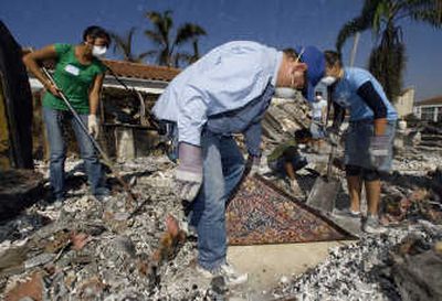 
Dust flies Friday as volunteers lift an antique Persian rug found under fiberglass insulation in the rubble of a burned home in Rancho Bernardo. Associated Press
 (Associated Press / The Spokesman-Review)