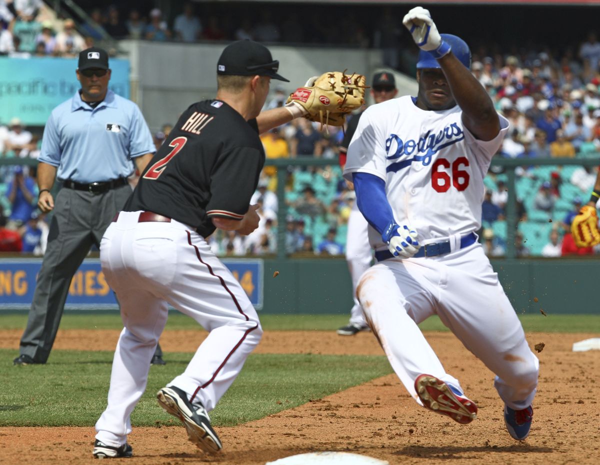 Arizona’s Aaron Hill tags out Los Angeles’ Yasiel Puig at first base during a rundown. (Associated Press)