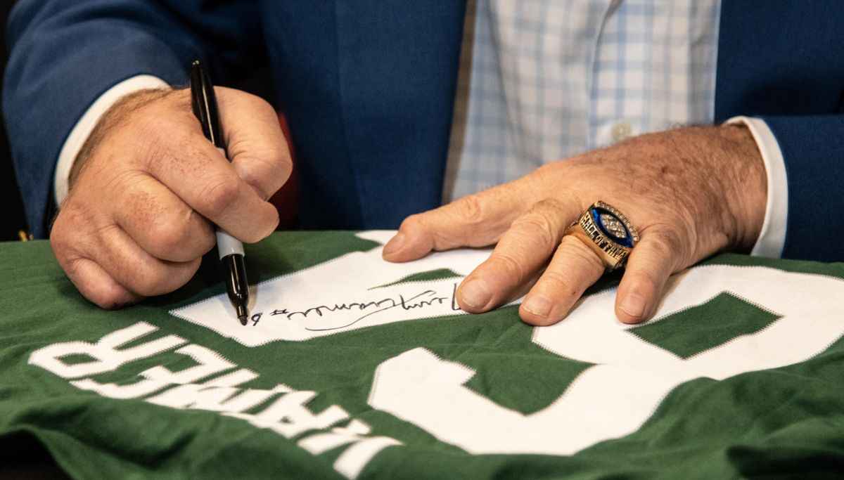 With a pen in one hand and an NFL Hall of Fame ring on the other, NFL Hall of Famer Jerry Kramer, who played in Super Bowls I and II. signs a fan