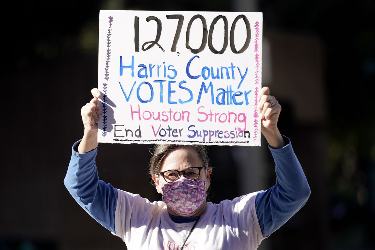 Demonstrator Gina Dusterhoft holds up a sign as she walks to join others standing across the street from the federal courthouse in Houston, Monday, Nov. 2, 2020, before a hearing in federal court involving drive-thru ballots cast in Harris County. The lawsuit was brought by conservative Texas activists, who have railed against expanded voting access in Harris County, in an effort to invalidate nearly 127,000 votes in Houston because the ballots were cast at drive-thru polling centers established during the pandemic.  (David J. Phillip)