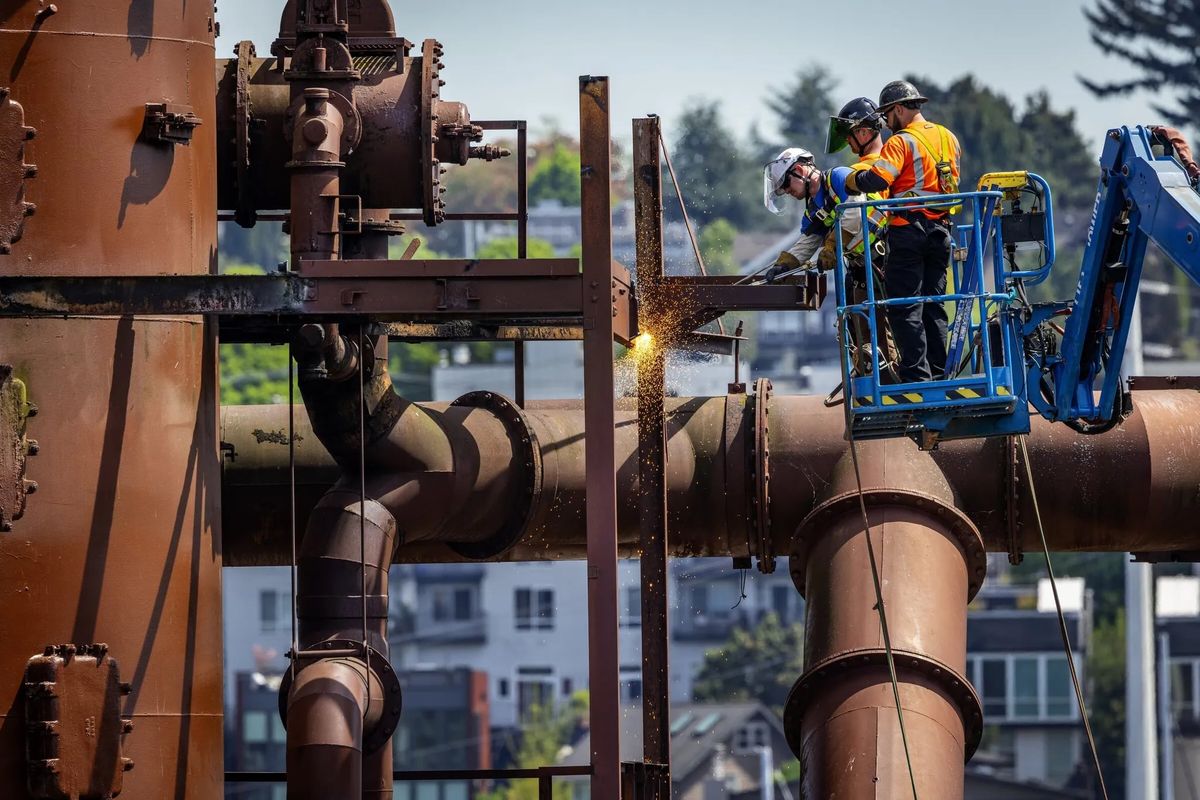 Using a cutting torch, crews work at removing catwalks, railings and other structures deemed dangerous at Gas Works Park on Monday in Seattle. (Ken Lambert/Seattle Times)