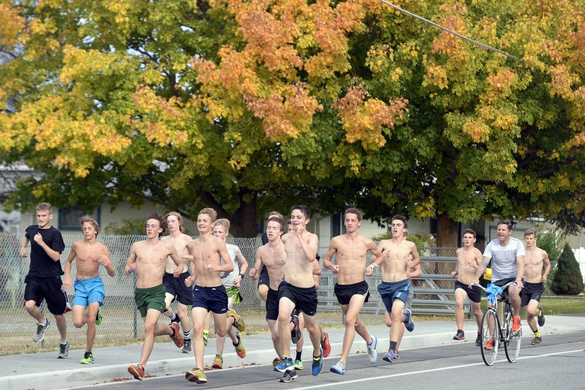 Coach Kieran Mahoney, right, follows the Central Valley Bears crosscountry team on a bicycle on their workout Monday, Oct. 12, 2015 at CVHS. JESSE TINSLEY jesset@spokesman.com (Jesse Tinsley / The Spokesman-Review)