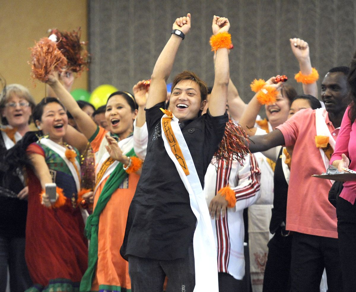 Gurung Roshan, of the Davenport Hotel, celebrates the completion of the mop relay race Tuesday in the ballroom at the Red Lion Hotel at the Park. Housekeepers from the Davenport and Hotel Lusso wore sashes with their home countries on them. (Jesse Tinsley)