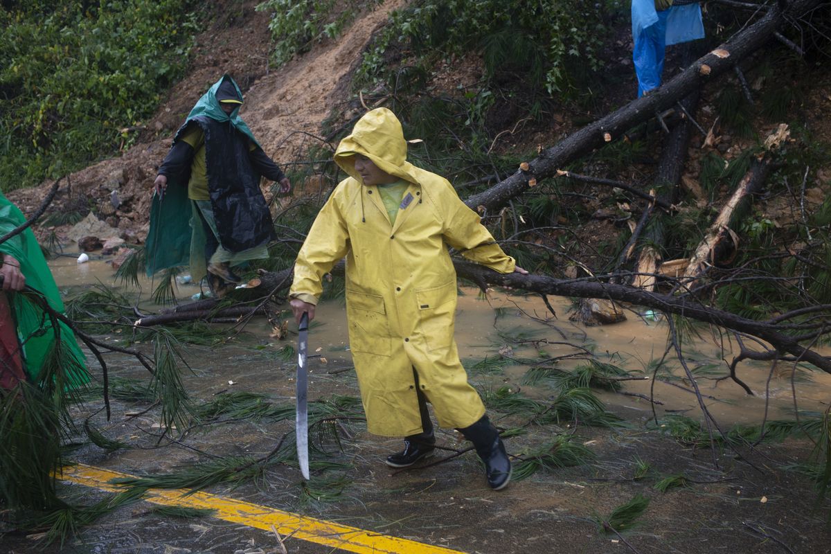 People clear branches Friday where a landslide blocked a road in Purulha, Guatemala.  (Associated Press)