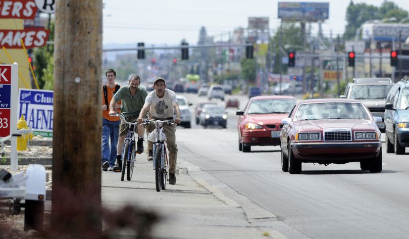 A pedestrian shares the sidewalk with bicyclists on Sprague Avenue, Tuesday. The City of Spokane Valley has outlined its proposed Bike and Pedestrian Master Program at a public hearing last week. (J. Bart Rayniak)
