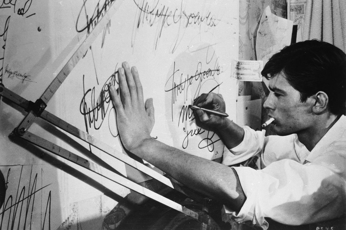 French actor Alain Delon smokes a cigarette as he practices forging a signature in a still from the film “Purple Noon,” based on the Patricia Highsmith novel “The Talented Mr. Ripley” and directed by Rene Clement, in 1960.  (Hulton Archive)