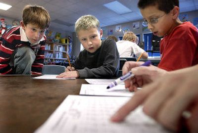 
Stephen Velardi, 8, Dutch Larson, 9, and Christian Robbins, 9, follow along as Reneta Gay grades their math assignments after school at Ness Elementary School.  The children are part of the school's extended-day program and stay at  school until 5 p.m. working on math, reading and writing. 
 (Joe Barrentine / The Spokesman-Review)