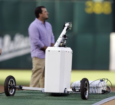 A telerobotic machine was operated by Nick LeGrande in Kansas City, Mo., to throw out the first pitch in Oakland. (Associated Press)