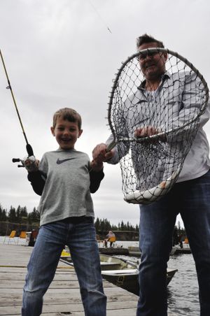 Quinn Connacher, 6, of Spokane celebrates catching his first trout while fishing off the dock at Bunker's Resort on Williams Lake with his stepfather, Andy Benson. They were fishing on April 28, 2013, the opening day of Washington's lowland trout fishing season. (Rich Landers)