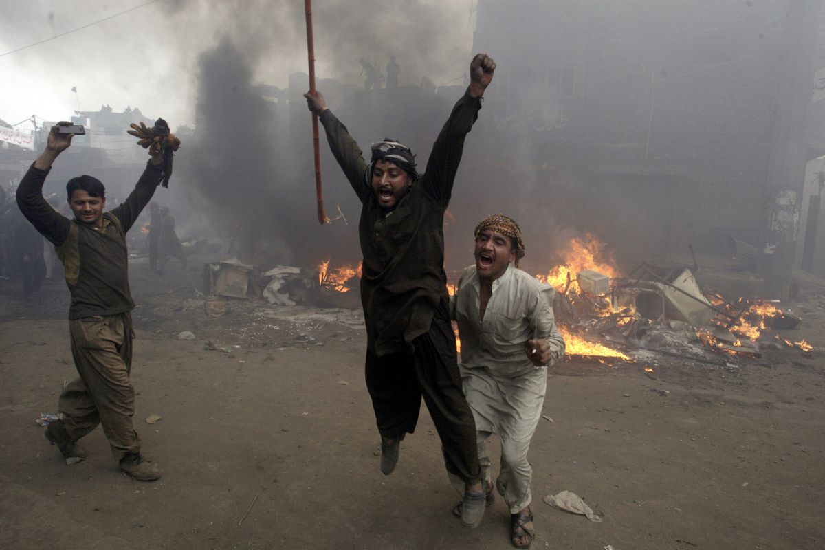 Pakistani men, part of an angry mob, react after burning belongings of Christian families in Lahore, Pakistan, Saturday. (Associated Press)