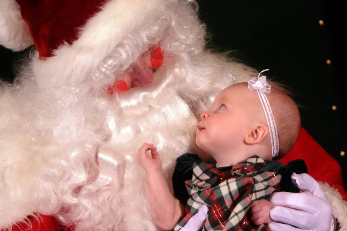 Hailee Delozier looks at Santa Claus for the very first time Tuesday. The 6-month-old was photographed with Dave Lewis, who works at Humanix, and volunteered with fellow workers to help families get holiday photos  at Spokane Valley Partners. Pixeldust Studio donated the photography. (J. BART RAYNIAK)