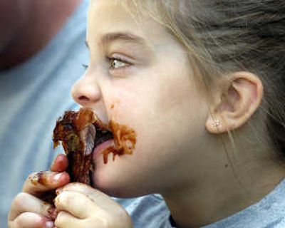 
Regan Oliver of Davenport, Wash., has her hands full with a messy piece of barbecue rib during last year's Pig Out in the Park.  
 (File / The Spokesman-Review)