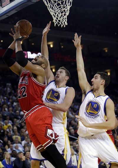 Chicago’s Taj Gibson beats Golden State’s David Lee, center, and Klay Thompson to the basket in the Bulls’ 113-111 victory in overtime on Tuesday night in Oakland, California. (Associated Press)