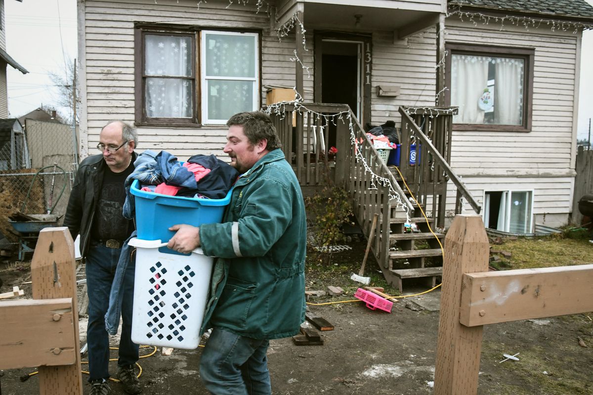 P.J. Farrell carries clothing past his father, Paul Farrell, after a blaze and smoke drove them from the home at 1311 E. Baldwin Ave. Christmas morning, Dec. 25, 2018. (Dan Pelle / The Spokesman-Review)