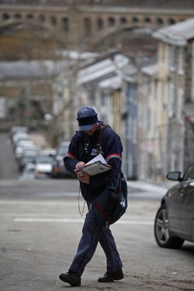 Kevin Pownall delivers mail in Philadelphia on Tuesday. The U.S. Postal Service is increasing the pressure for dropping Saturday home delivery.  (Associated Press)