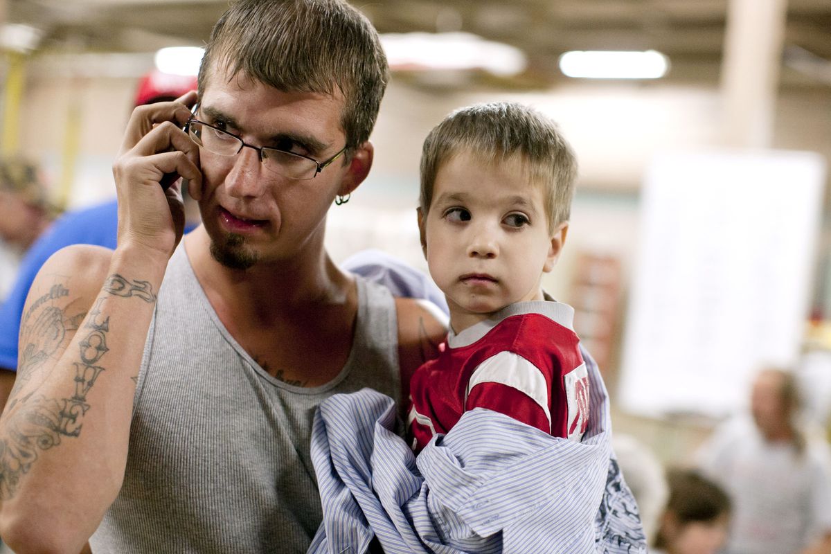 Jeffrey Scott, left, places a call as he holds his son, Joshua, after they were forced to evacuate their Fourth Street home on Friday, Sept. 14, 2012, at the Mishawaka, Ind. Fire Station. Police and firefighters evacuated a large area of Mishawaka after a reported chemical fire at an abandoned factory. (James Brosher / South Bend Tribune)