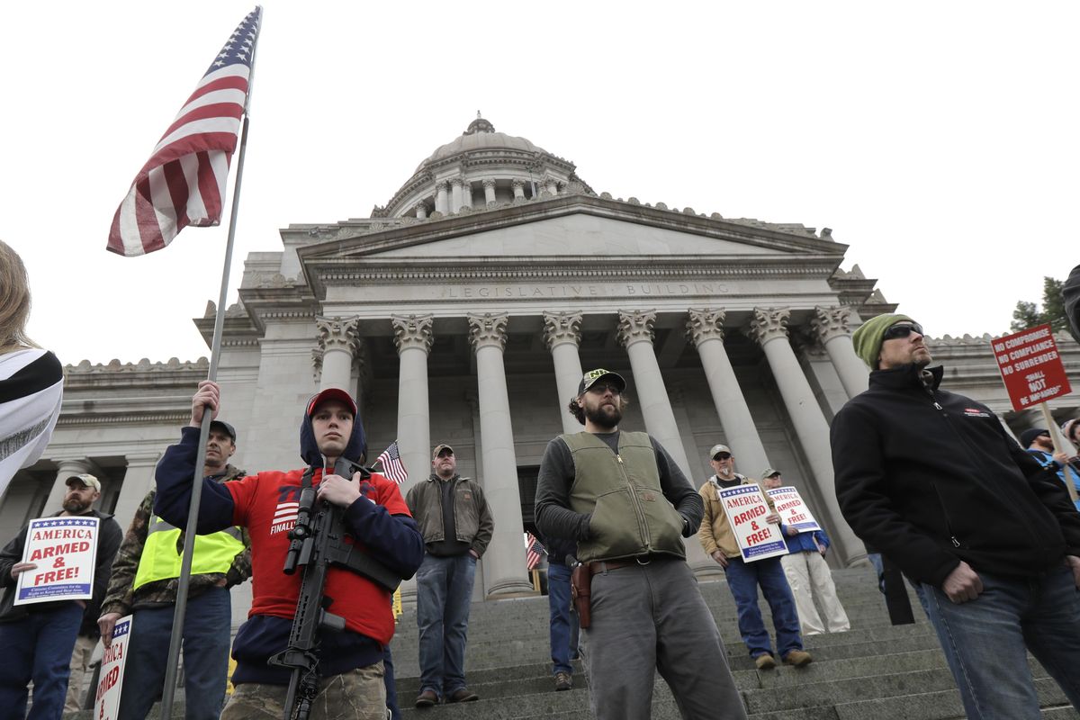 Micheal Thompson, left, holds a an AR-15 rifle and a U.S. flag as he takes part in a gun-rights rally, Friday, Jan. 18, 2019, at the Capitol in Olympia, Wash. (AP Photo/Ted S. Warren) ORG XMIT: WATW103 (Ted S. Warren / AP)