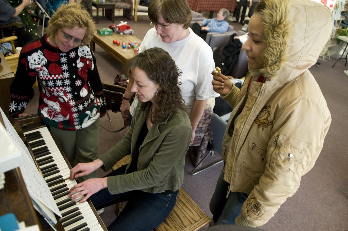 At the Women’s Hearth, volunteer Stephanie Burgess plays Christmas carols for, from left,  Sandy Wiedeman, Cindy Curran and Shalena Bromley. The number of homeless and low-income women who use the drop-in center has increased from  100 a day to 130 a day. Transitions, which oversees the center, recently met a fundraising goal, but leaders say per-person donations are below average.  (Colin Mulvany / The Spokesman-Review)