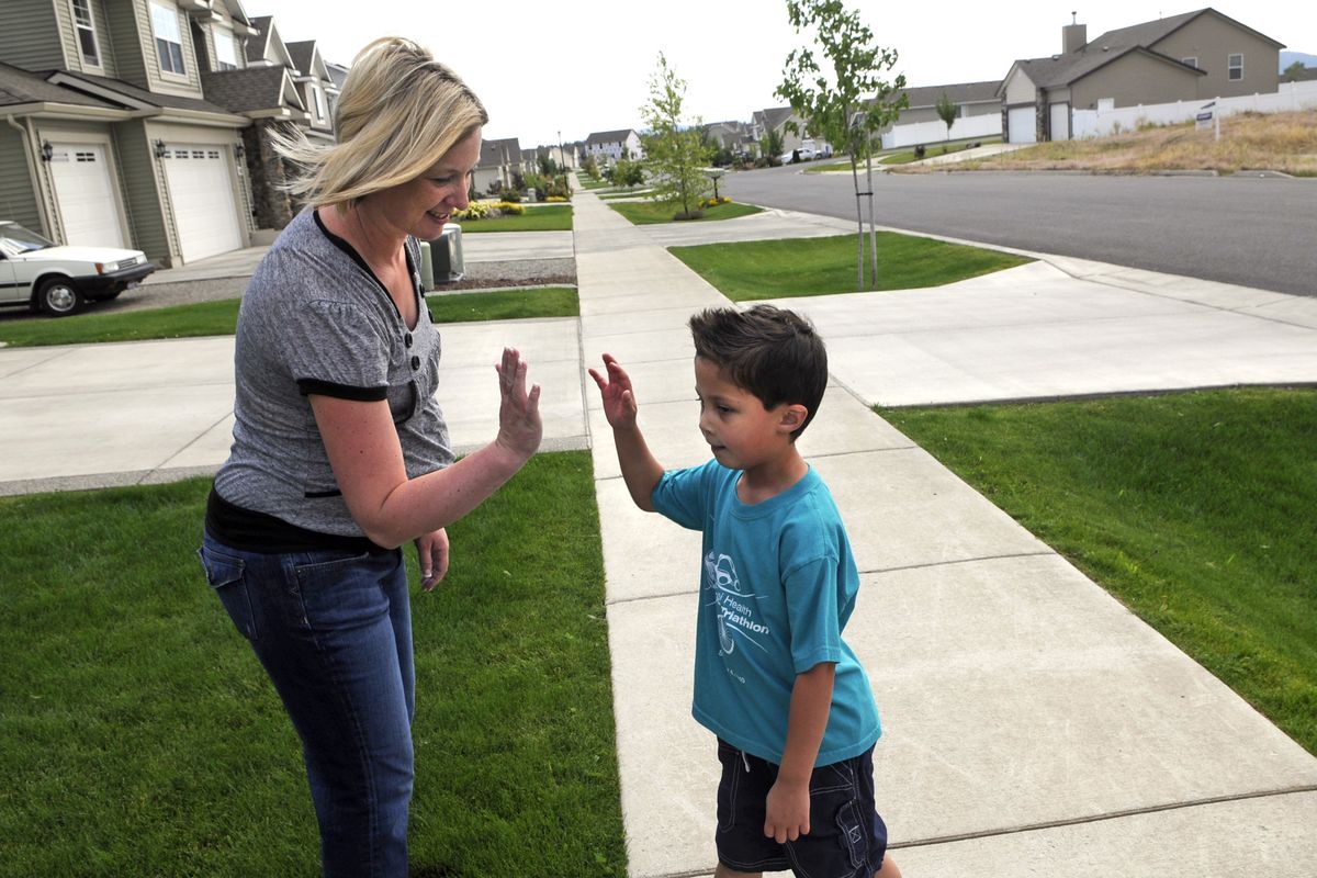 After a few laps around the yard in 90-degree weather, a tired Joey Bonacci, 5, gets a high-five from his mother, Nicky Flagor, on Monday at their home in Hayden. Joey will be participating in the Kootenai Health Triathlon for Kids on Sept. 3. (Dan Pelle)