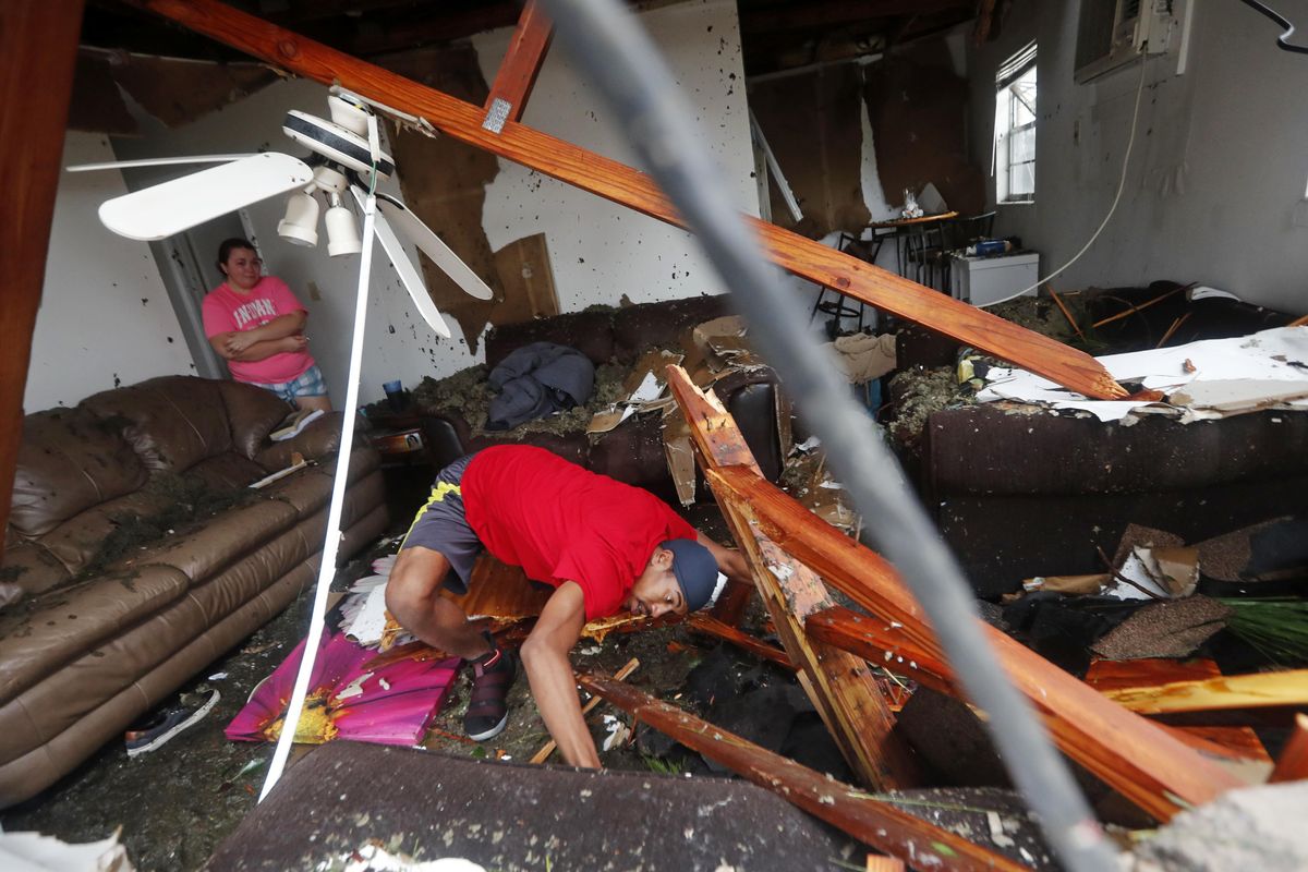 Dorian Carter looks under furniture for a missing cat after several trees fell on their home during Hurricane Michael in Panama City, Fla., Wednesday, Oct. 10, 2018. Supercharged by abnormally warm waters in the Gulf of Mexico, Hurricane Michael slammed into the Florida Panhandle with terrifying winds of 155 mph Wednesday, splintering homes and submerging neighborhoods. (Gerald Herbert / Associated Press)