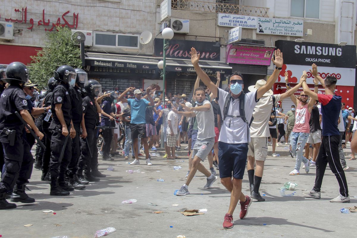 Protesters face Tunisian police officers during a demonstration in Tunis, Tunisia, Sunday, July 25, 2021. Violent demonstrations broke out on Sunday in several Tunisian cities as protesters expressed anger at the deterioration of the country