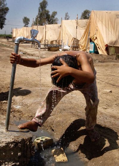 
A boy washes himself under an outdoor tap at a camp housing 23 Shiite families in Diwaniyah, Iraq. Continuing sectarian violence has caused increasing numbers of Iraqis to leave their homes. 
 (Associated Press / The Spokesman-Review)