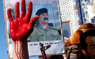 
An Iraqi holds out his hand, covered with sheep's blood, while protesters carry posters of former Iraqi president Saddam Hussein in Al-Dor,  Iraq, on Monday. 
 (Associated Press / The Spokesman-Review)
