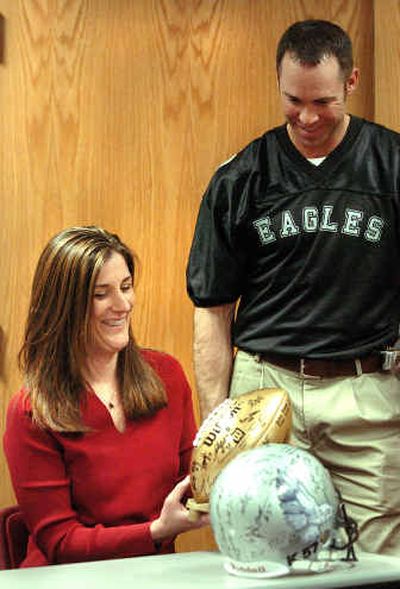 
Carrie Kralicek, wife of injured police Officer Michael Kralicek, accepts an autographed football from Coeur d'Alene Police Lt. Randy Miller of the Kootenai Eagles, who are dedicating their season to the wounded man.  
 (Jesse Tinsley / The Spokesman-Review)