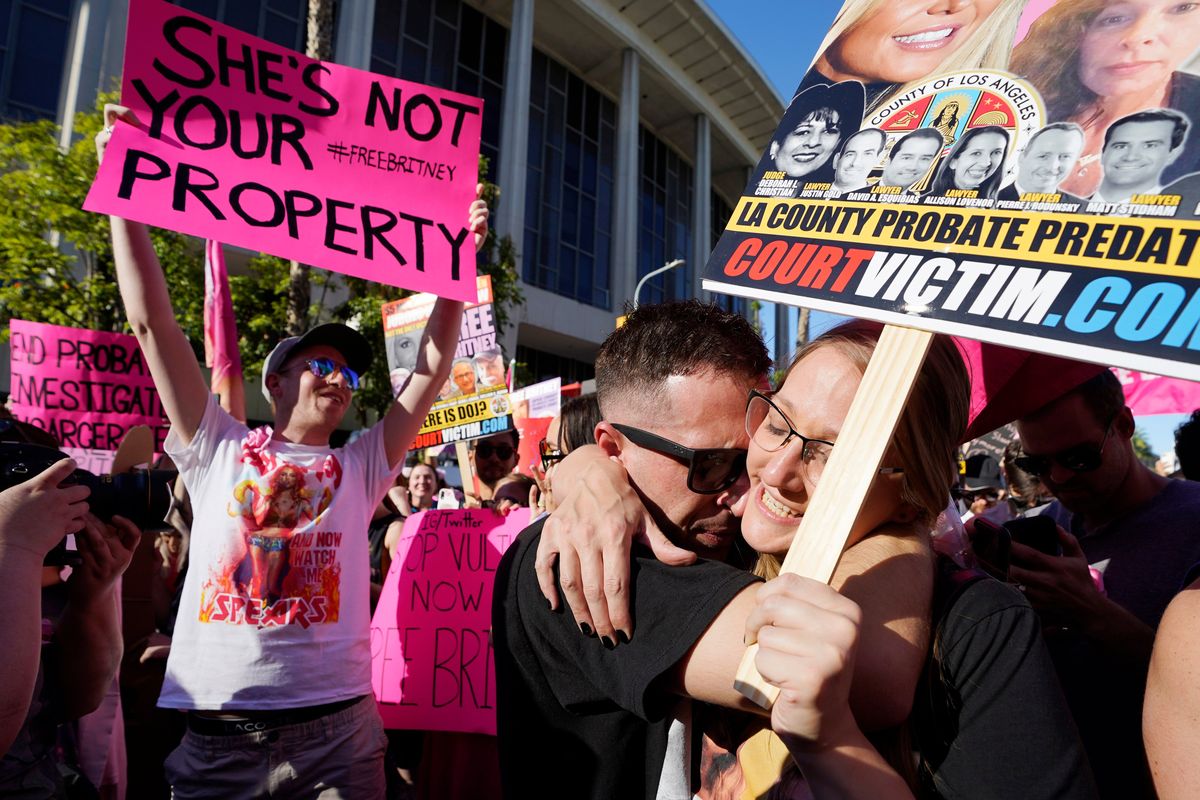 Britney Spears supporters Aaron Morris, second from right, and Elizabeth Crocker embrace outside a hearing concerning the pop singer's conservatorship at the Stanley Mosk Courthouse, Friday, Nov. 12, 2021, in Los Angeles. A Los Angeles judge ended the conservatorship that has controlled Spears' life and money for nearly 14 years.  (Chris Pizzello)