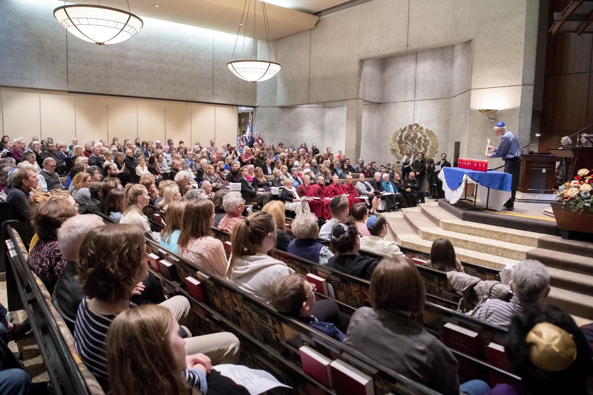 As Arthur Zack lights a candle at far right, a standing-room only crowd, with hundreds in overflow areas, watches, Tuesday, Oct. 30, 2018, at Temple Beth Shalom on Spokane’s South Hill. The crowd gathered to mourn the dead from the mass shooting at Tree of Life in Pittsburgh, Pennsylvania. (Jesse Tinsley / The Spokesman-Review)