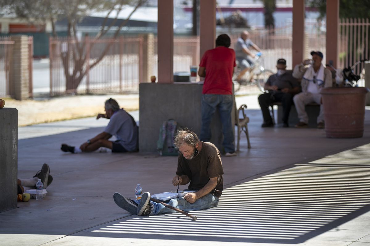 The homeless and those in need of a free meal can no longer eat in the lunchroom at Martha’s Village & Kitchen in Indio, California, due to COVID-19, leaving them to sit in the shade outside as they try to escape the blazing sun.  (Allen J. Schaben//Los Angeles Times)