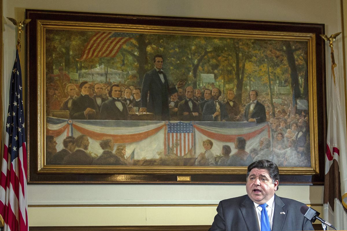 In this May 22, 2020 file photo, Illinois Gov. JB Pritzker answers questions from the media, from his office at the Illinois State Capitol, in Springfield, Ill., in front of a painting painting depicting a political debate in Charleston, Ill., on Sept. 18, 1858 between Stephen A. Douglas and Abraham Lincoln./The State Journal-Register via AP)  (Justin L. Fowler)
