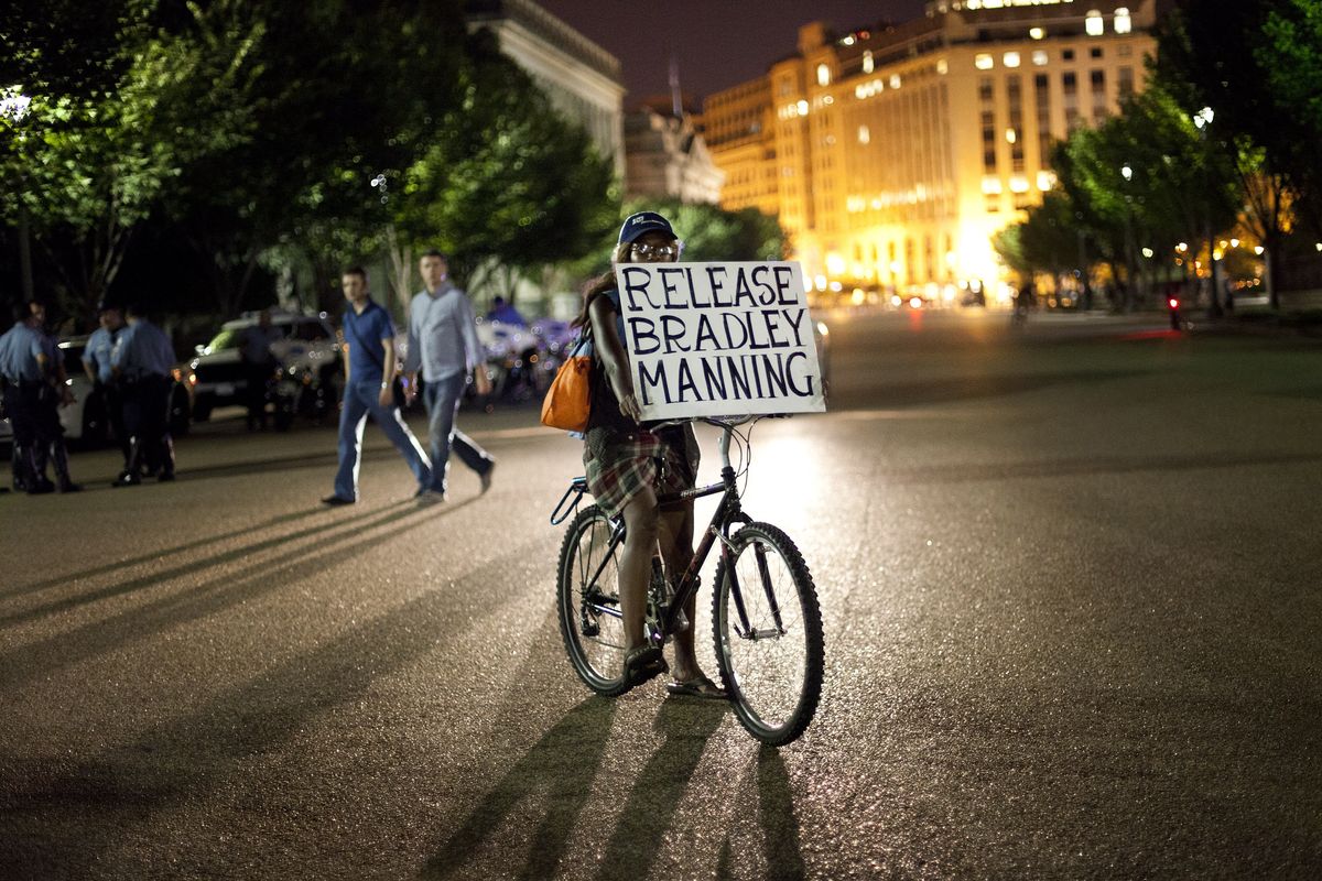 A supporter of Army Pfc. Bradley Manning carries a sign while on a bicycle during a nighttime demonstration in front of the White House in Washington, D.C., on Tuesday. (Associated Press)