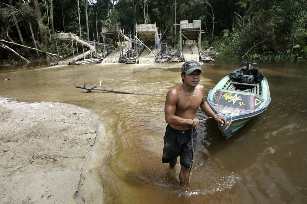 A traditional gold miner tows a boat at a mine on Takaras river in Kasongan, Indonesia. (Dita Alangkara / The Spokesman-Review)